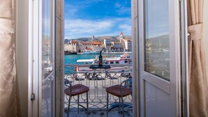 A balcony with two chairs and a table, overlooking a marina with boats and a historic building with a red roof. - Vila Liza (Trogir)