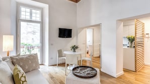 A modern living room with a sofa, a dining table, and a TV. - Trevi Beau Boutique Hotel (Rome)