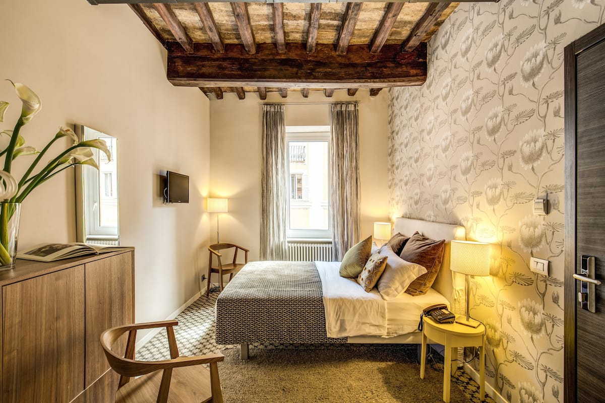 A bedroom with a bed, bedside table, lamp, and a wooden chair.