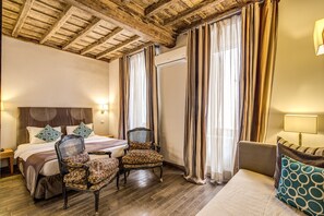 A hotel room with a wooden ceiling, a bed with a headboard, two armchairs, a sofa, and curtains. - Trevi Beau Boutique Hotel (Rome)