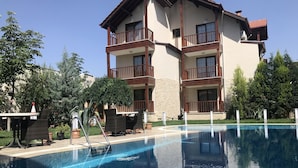 A multi-story hotel with a swimming pool, outdoor seating, and lush greenery. - Venus Hotel (Denizli)