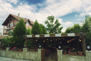 A covered outdoor seating area with potted plants and a building in the background. - Venus Hotel (Denizli)