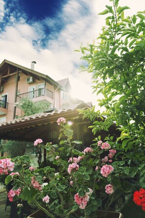 A building with a balcony and a garden with pink flowers. - Venus Hotel (Denizli)