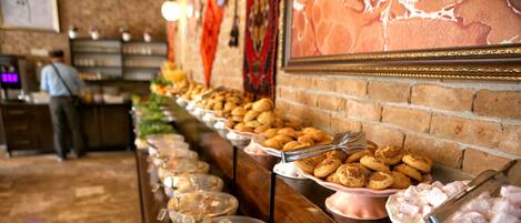 A buffet with various food items and a man in the background.
