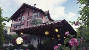A multi-story building with balconies, a covered patio area with hanging lights, and surrounding greenery. - Venus Hotel (Denizli)