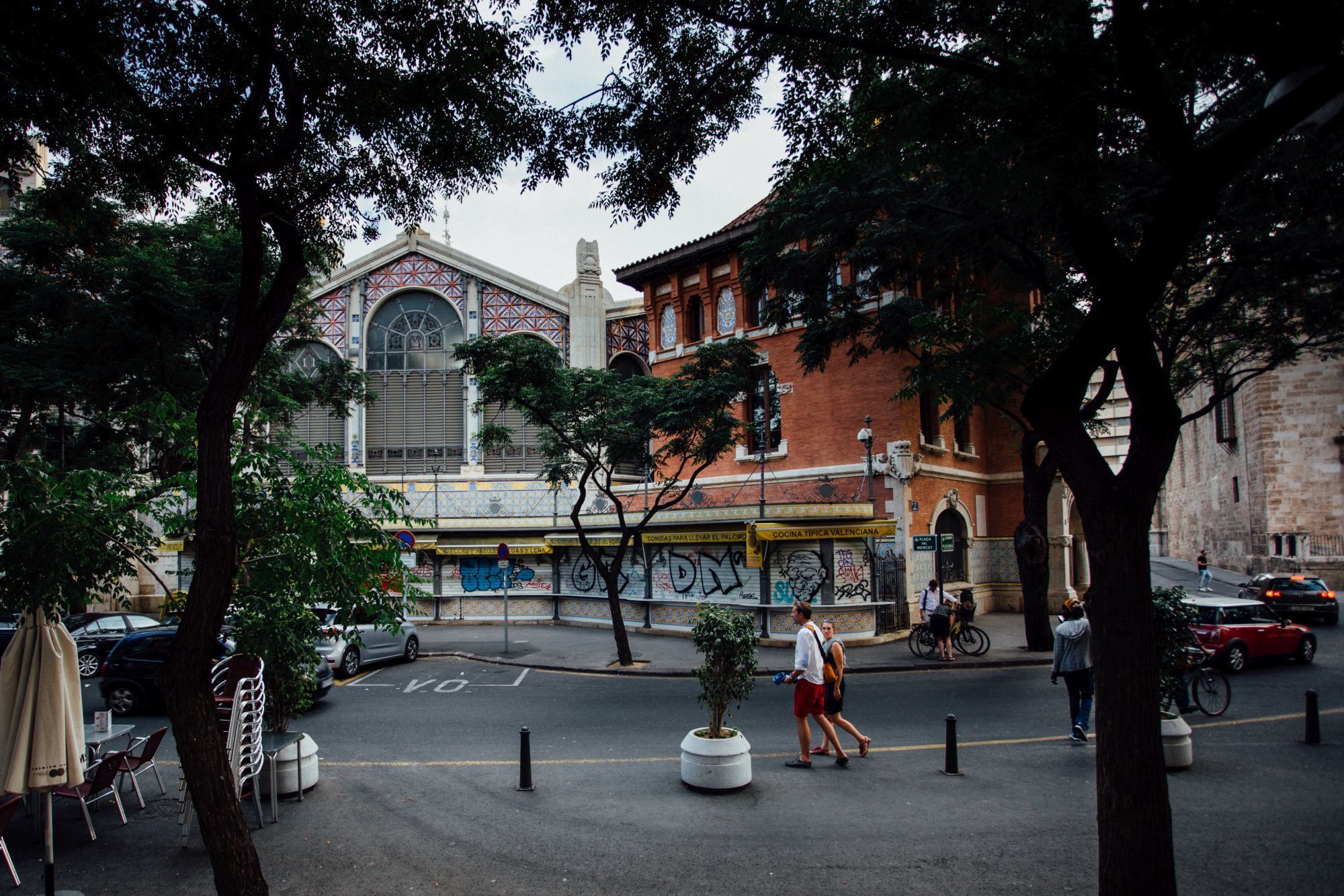 Escena callejera con un edificio que presenta un amplio ventanal en arco y fachada de azulejos.
