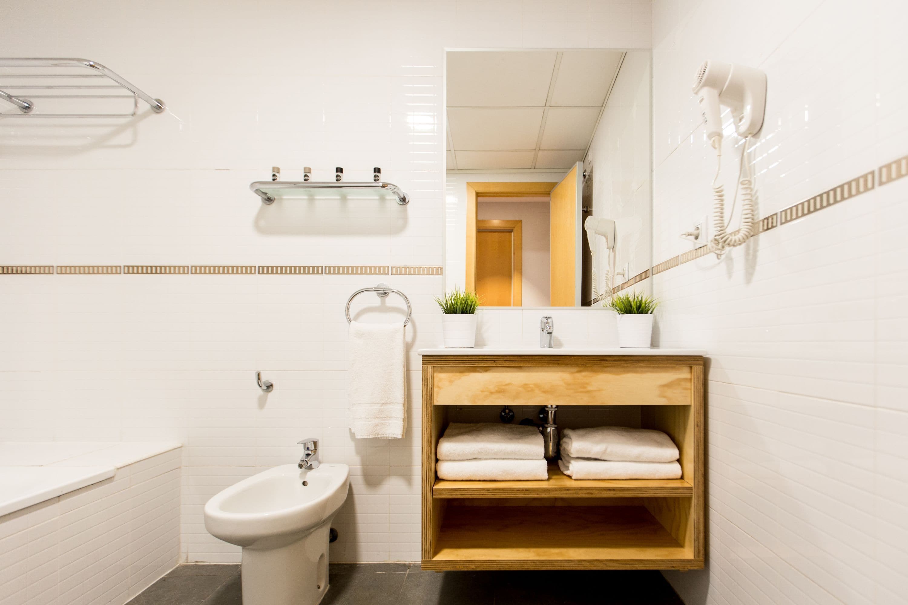 A modern bathroom with a wooden vanity, a bidet, and a towel rack.