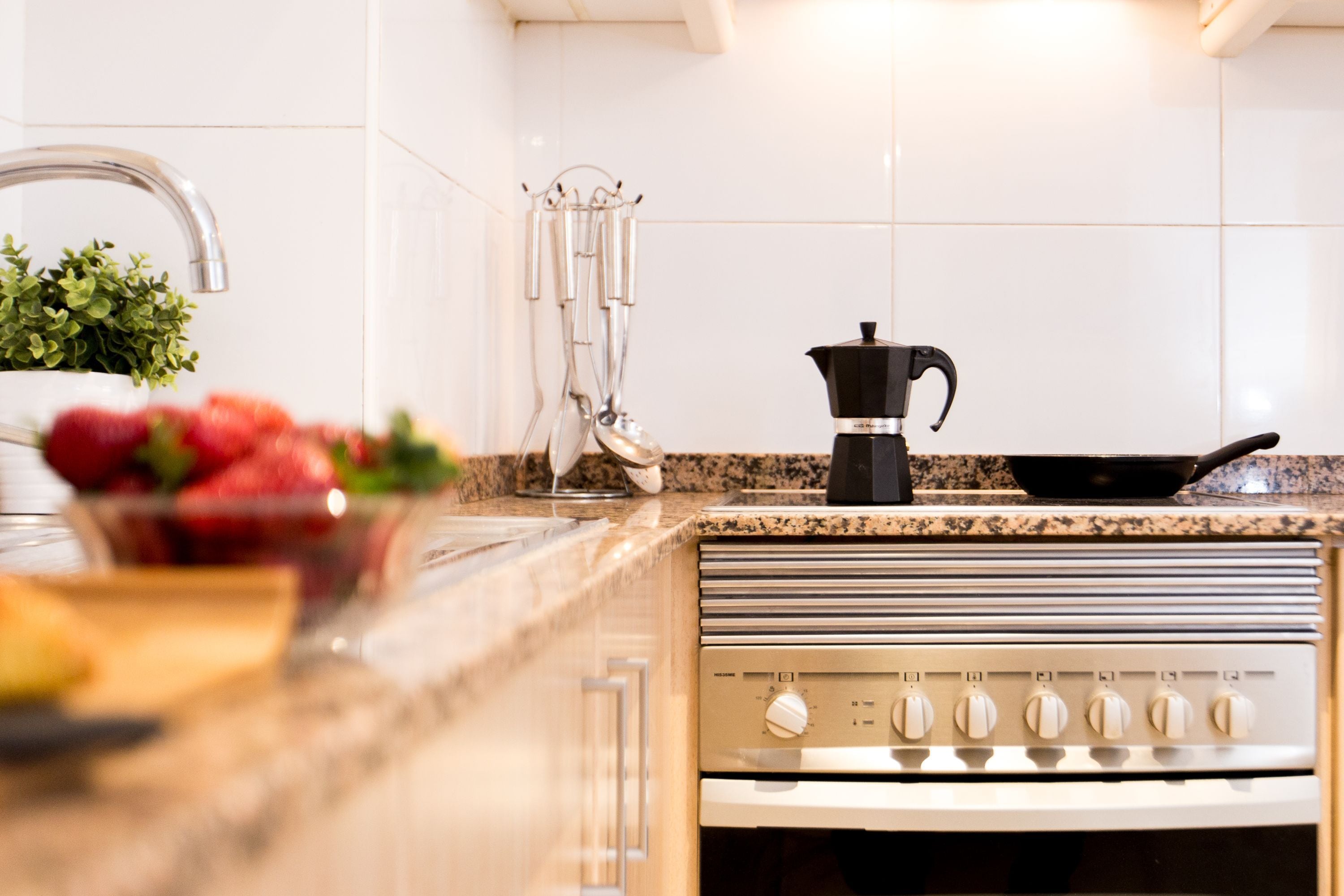 Una cocina con encimera de granito, electrodomésticos de acero inoxidable y una cafetera.