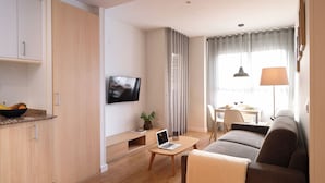 Een moderne woonkamer met een bank, een salontafel, een televisie, en een eethoek met een tafel en stoelen.