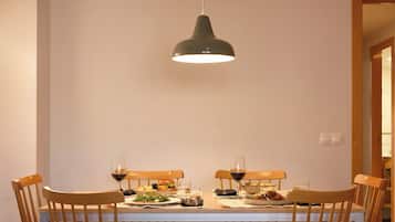 A dining table with chairs, a hanging light fixture, and a meal set.