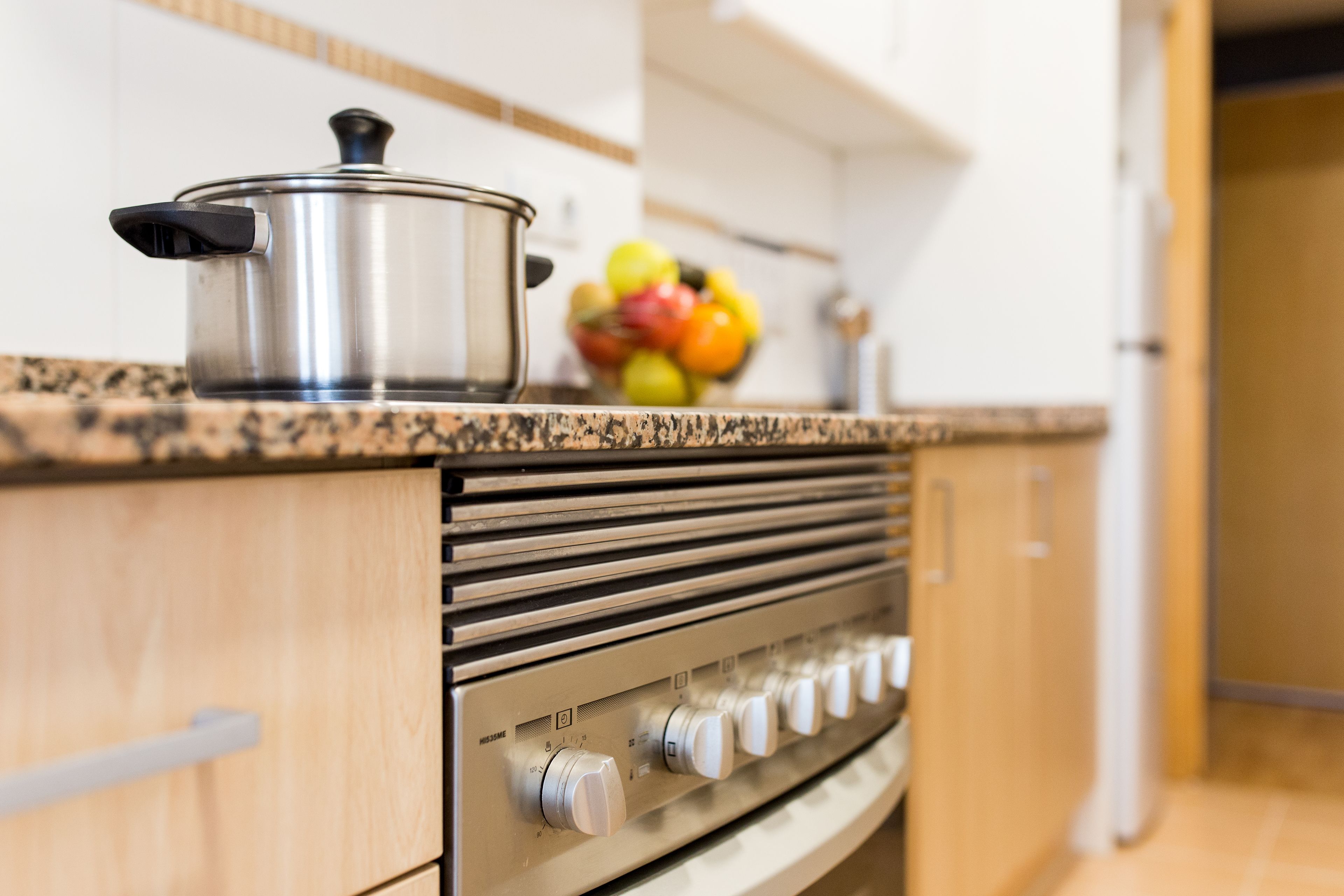 Una cucina con un piano cottura in acciaio inossidabile, mobili in legno e un piano di lavoro in granito.