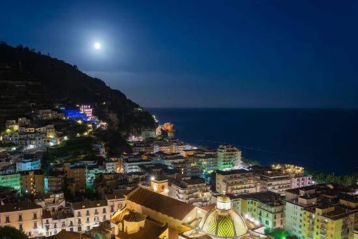 A coastal town at night with illuminated buildings and a prominent church dome.