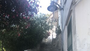 A set of stone steps leading up to a building with a white wall and a green door. - Palazzo Cocò (Maiori)