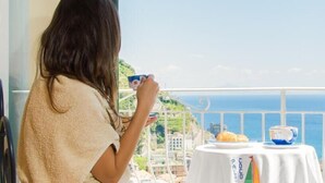 A person enjoying a meal on a balcony with a scenic view of the sea and a coastal town. - Palazzo Cocò (Maiori)