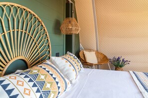 Una cama con cabecera de ratán, una mesita de noche de mimbre y una lámpara de pie tejida.