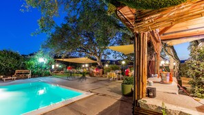 A swimming pool with a wooden deck, outdoor seating, and a pergola. - Hotel Glamping Borgo di Campagna (Loiri Porto San Paolo)