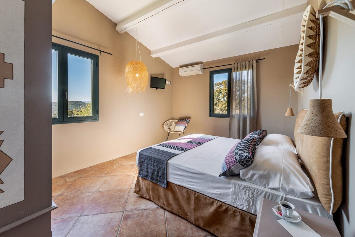 Un dormitorio con cama, una silla, un ventanal y aire acondicionado instalado en la pared.