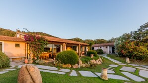 A house with a patio, stone pathway, and garden with rocks and plants. - Hotel Glamping Borgo di Campagna (Loiri Porto San Paolo)