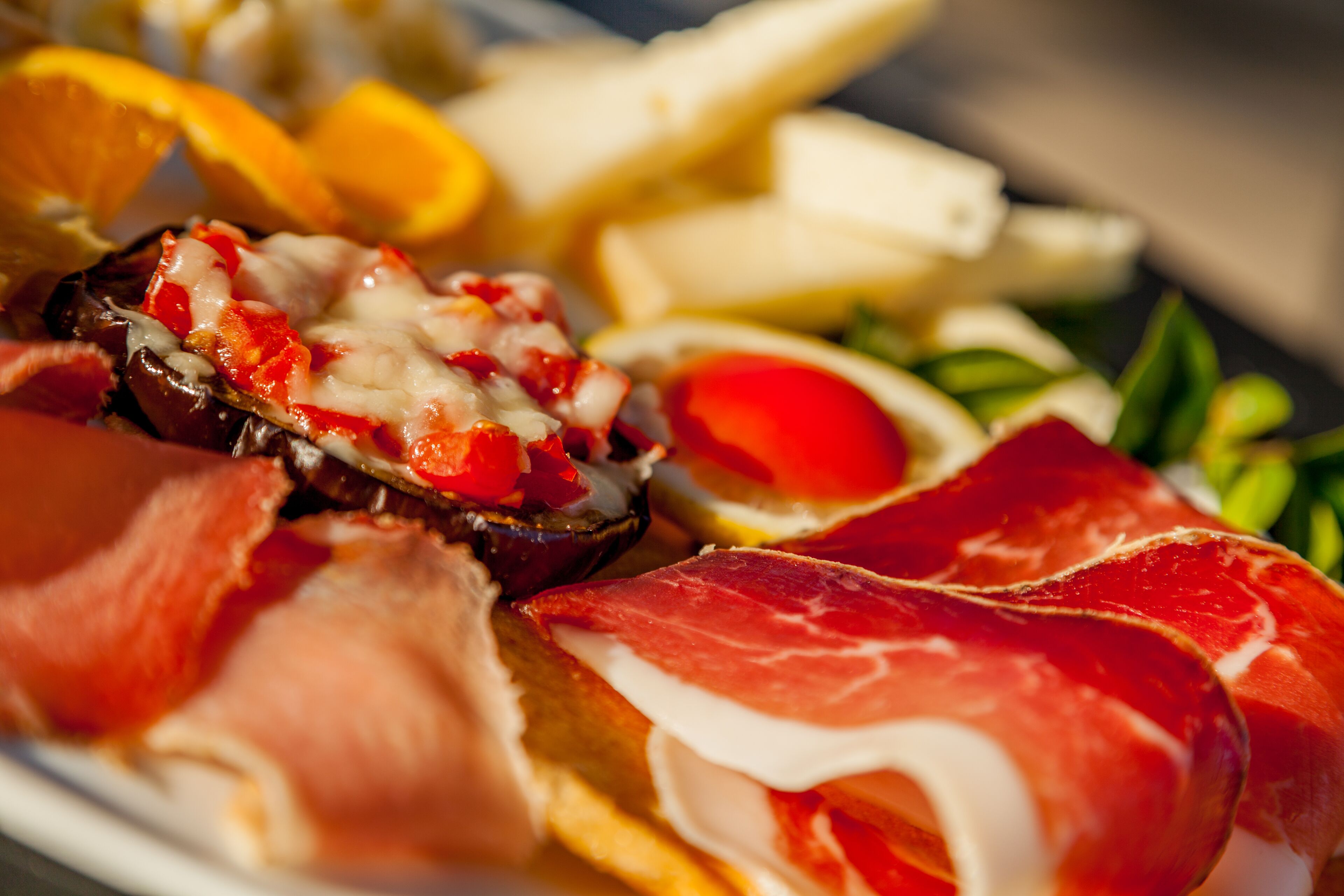 Un plato de comida con jamón serrano, queso y un champiñón relleno.