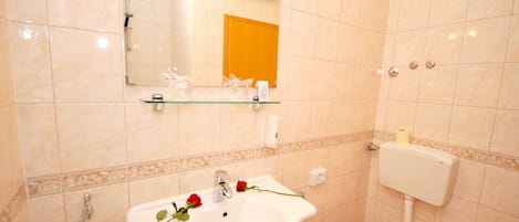 Un bagno con lavandino, WC e ripiano in vetro sopra il lavandino.