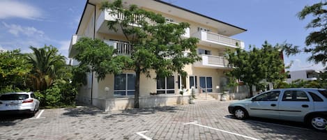 A multi-story building with a parking area in front.