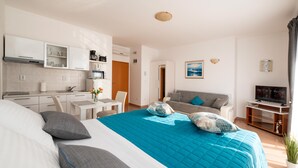 A modern hotel room with a large bed, a separate dining area, a sofa, a TV, and a kitchenette. - Apartmani Trogir (Trogir)