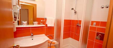 Une salle de bain avec un lavabo, un miroir, une douche et des murs recouverts de carreaux orange.