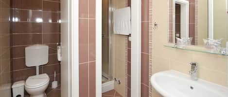A bathroom with a toilet, shower, and sink.