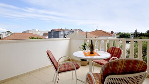A balcony with a round table, two chairs, and a bottle of wine. - Apartmani Trogir (Trogir)