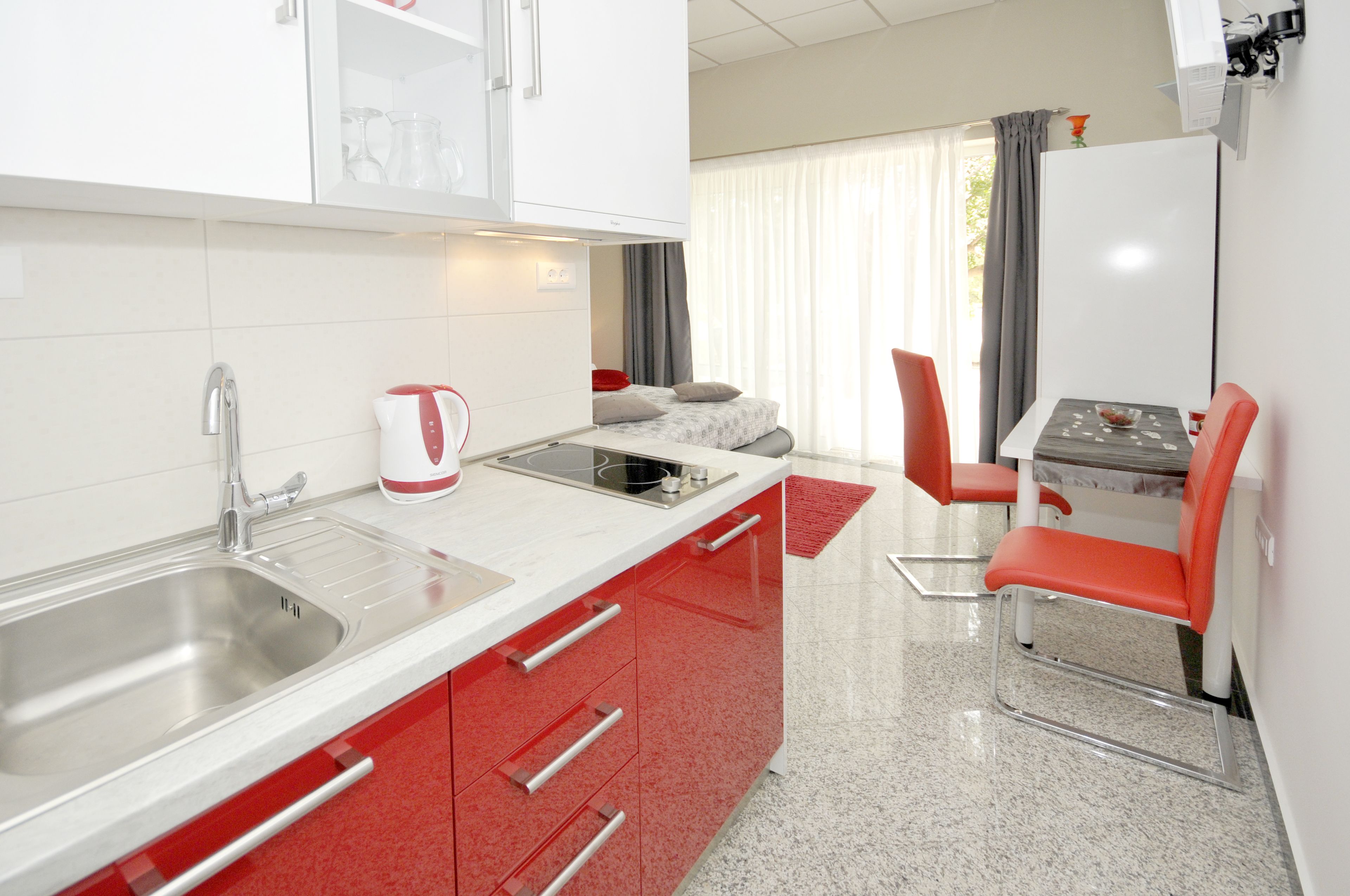 A compact kitchen with a sink, stove, and dining area with chairs.