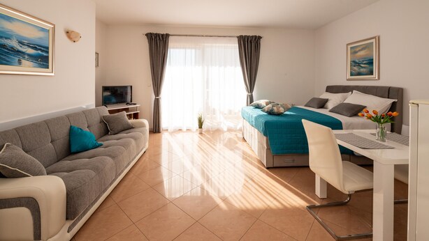 A modern hotel room with a bed, a sofa, a desk, and a television. - Apartmani Trogir (Trogir)