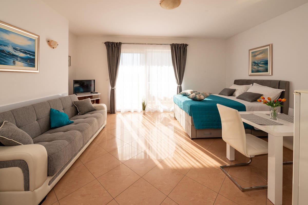 Una habitación de hotel moderna con cama, sofá, escritorio y televisión.
