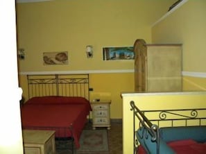 A room with two beds, a wooden cabinet, and a small table.