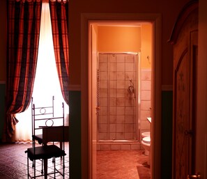 Une salle de bain avec une douche, des toilettes et une chaise.