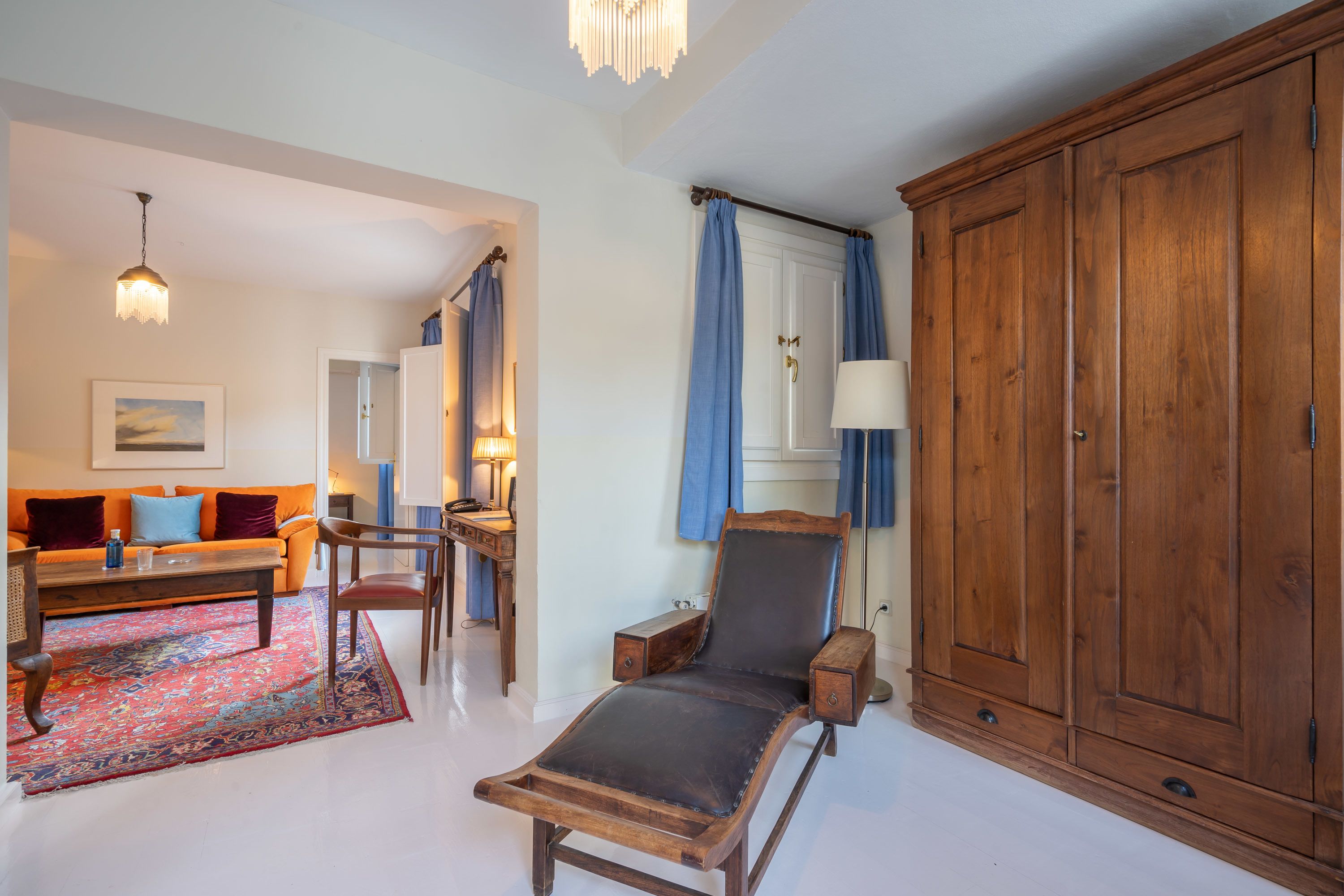 Een woonkamer met een houten stoel, een bank, een salontafel en een grote houten garderobe.