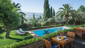Un espace piscine avec des chaises longues, une table à manger pour deux personnes et une vue sur la campagne.