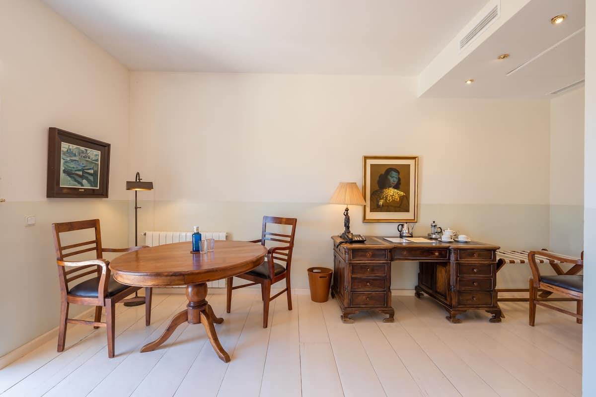 Un coin repas avec une table et des chaises en bois, un bureau avec des tiroirs et deux tableaux encadrés accrochés aux murs.