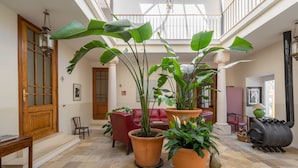 Un hall d’entrée spacieux, agrémenté de grands pots de plantes, d’une cheminée et d’un plafond haut laissant entrer la lumière naturelle.