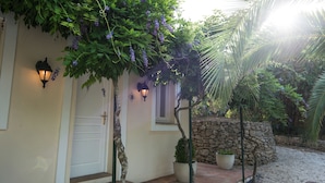 Une maison avec une porte blanche, un mur en pierre et un pot de fleurs.