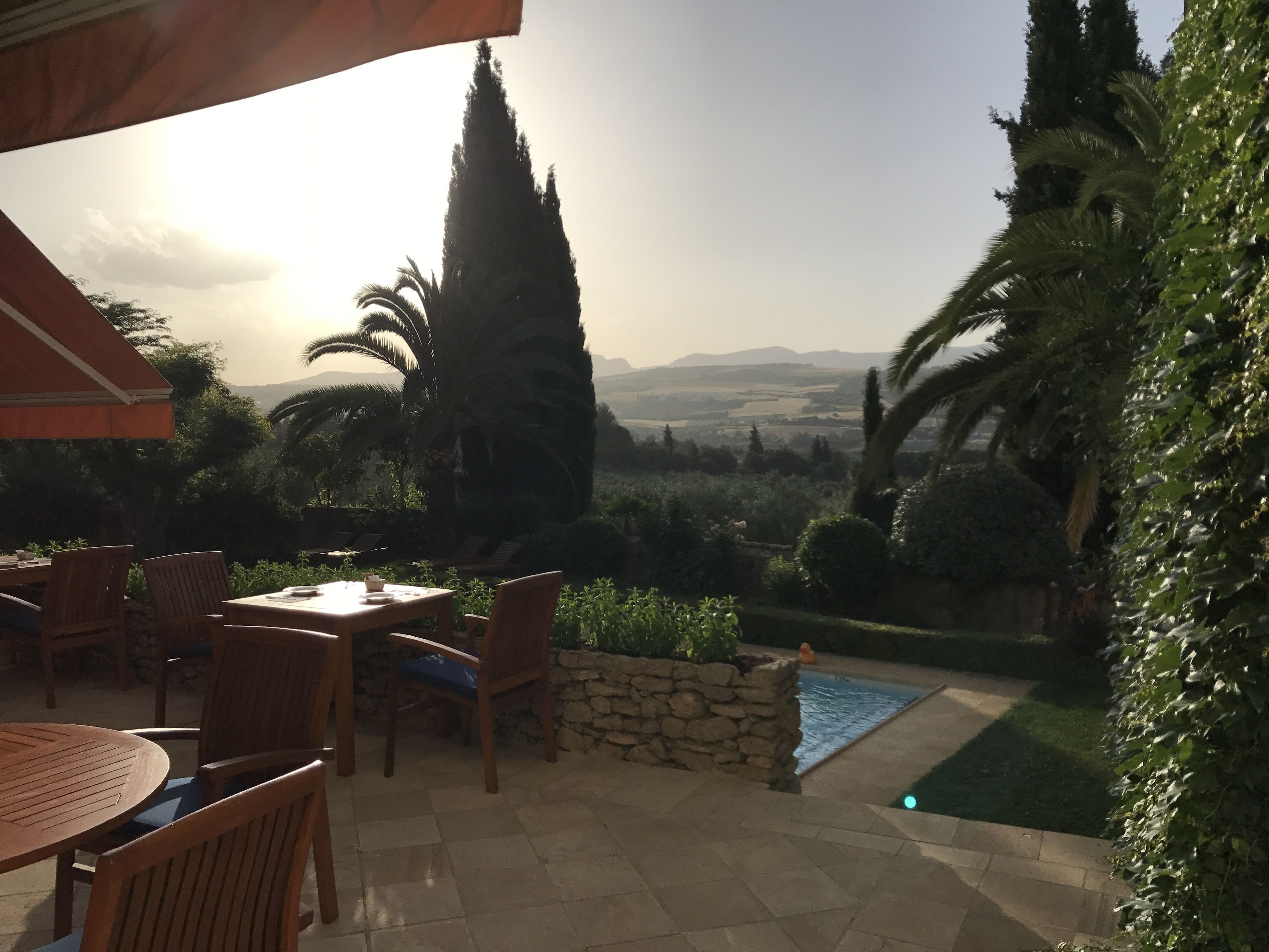 A patio with a table and chairs, a stone wall, and a view of the landscape.