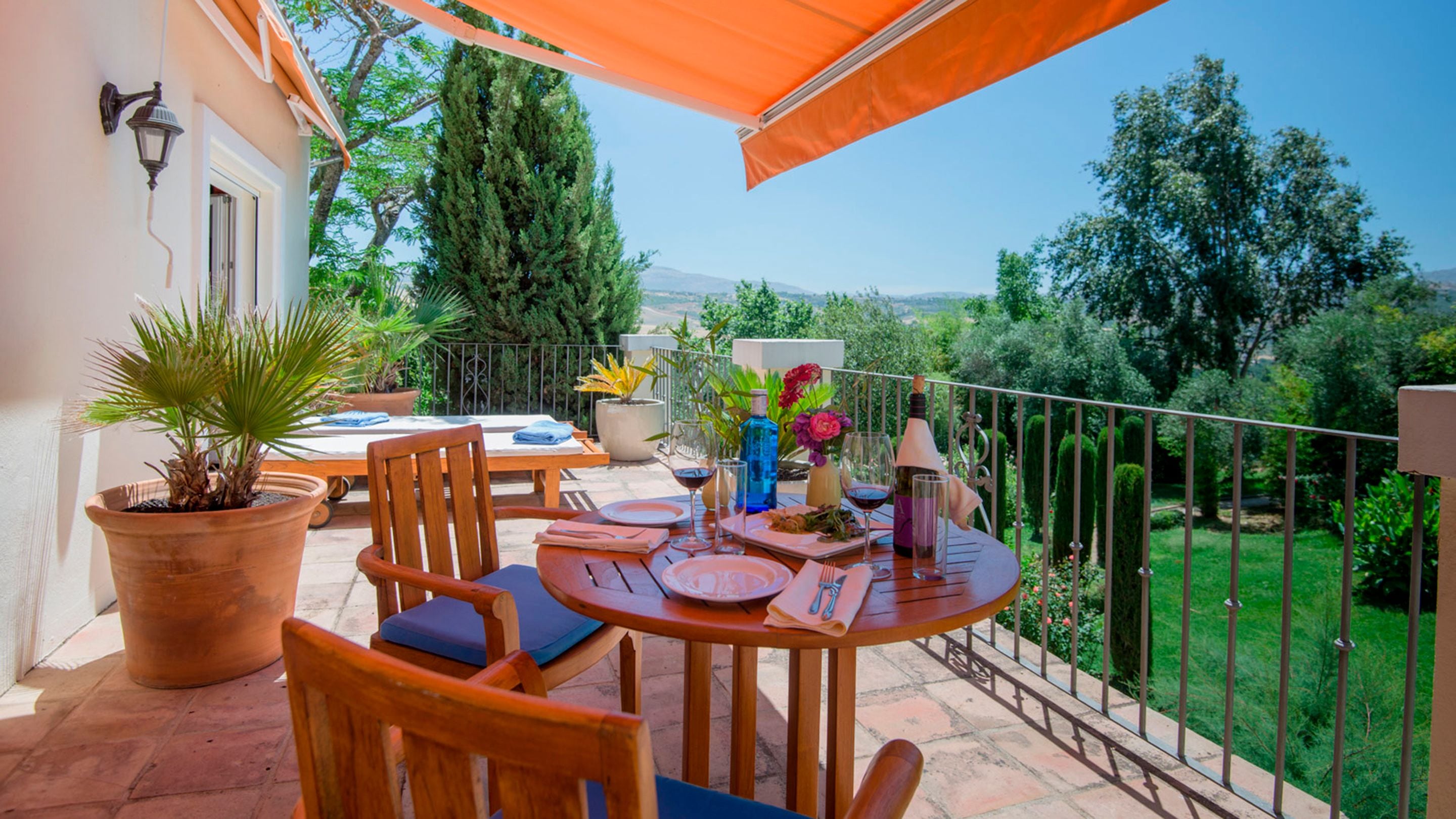 Eine Terrasse im Freien mit Esstisch, umgeben von Kübelpflanzen und Blick ins Grüne.