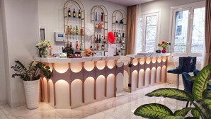 A hotel reception area with a marble floor, a reception desk with integrated lighting, a glass display case with various items, and a window with curtains. - CSI Group - Hotel Central Station (Milan)