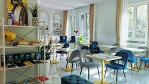 A modern dining area with tables and chairs, a globe on a shelf, and a bookshelf with books and decorative items. - CSI Group - Hotel Central Station (Milan)