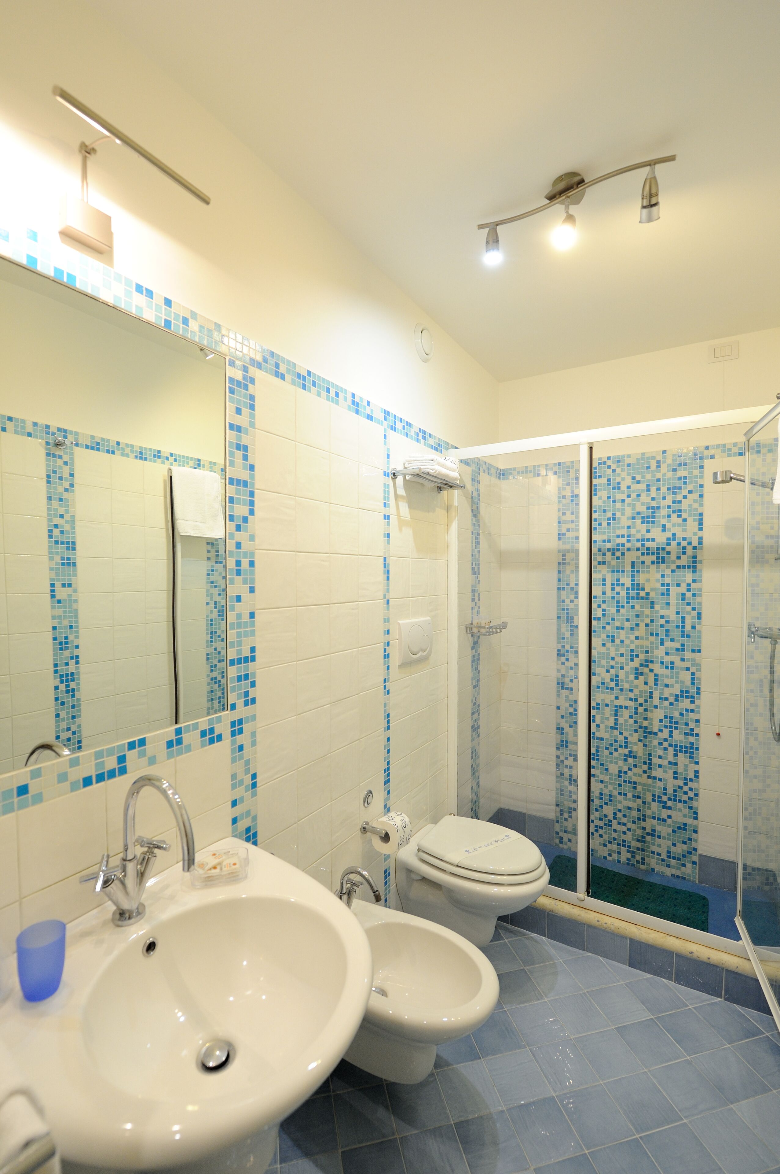 Ein Badezimmer mit Waschbecken, zwei Toiletten, einer Dusche und einem Spiegel.