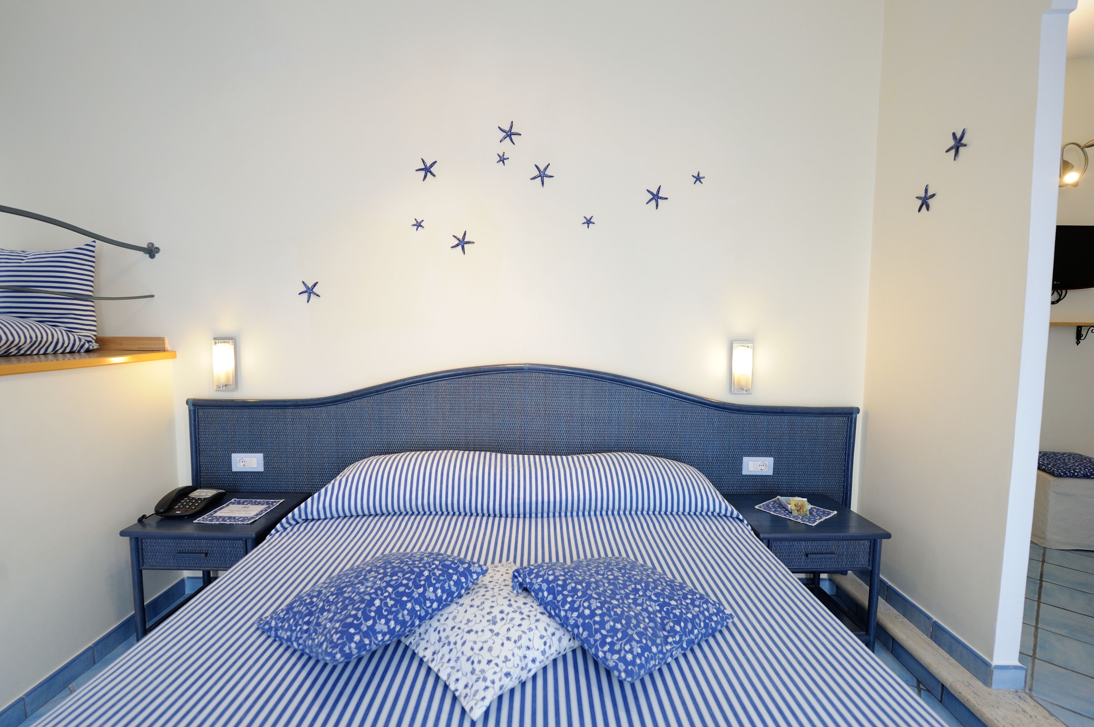 A neatly made bed with striped bedding and star-shaped wall decorations.