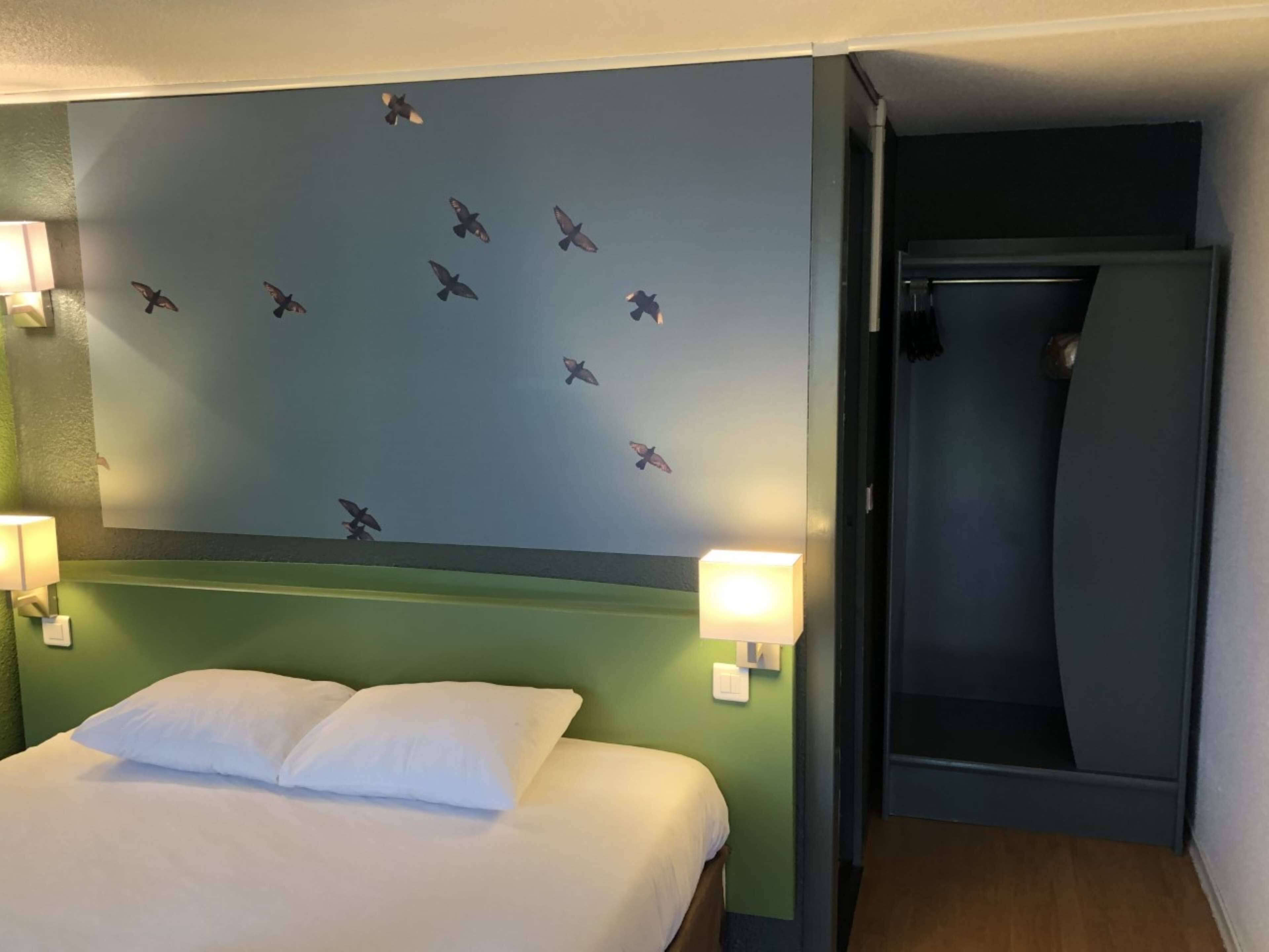 Una habitación de hotel con una cama, una pared con calcomanías de aviones y una puerta.