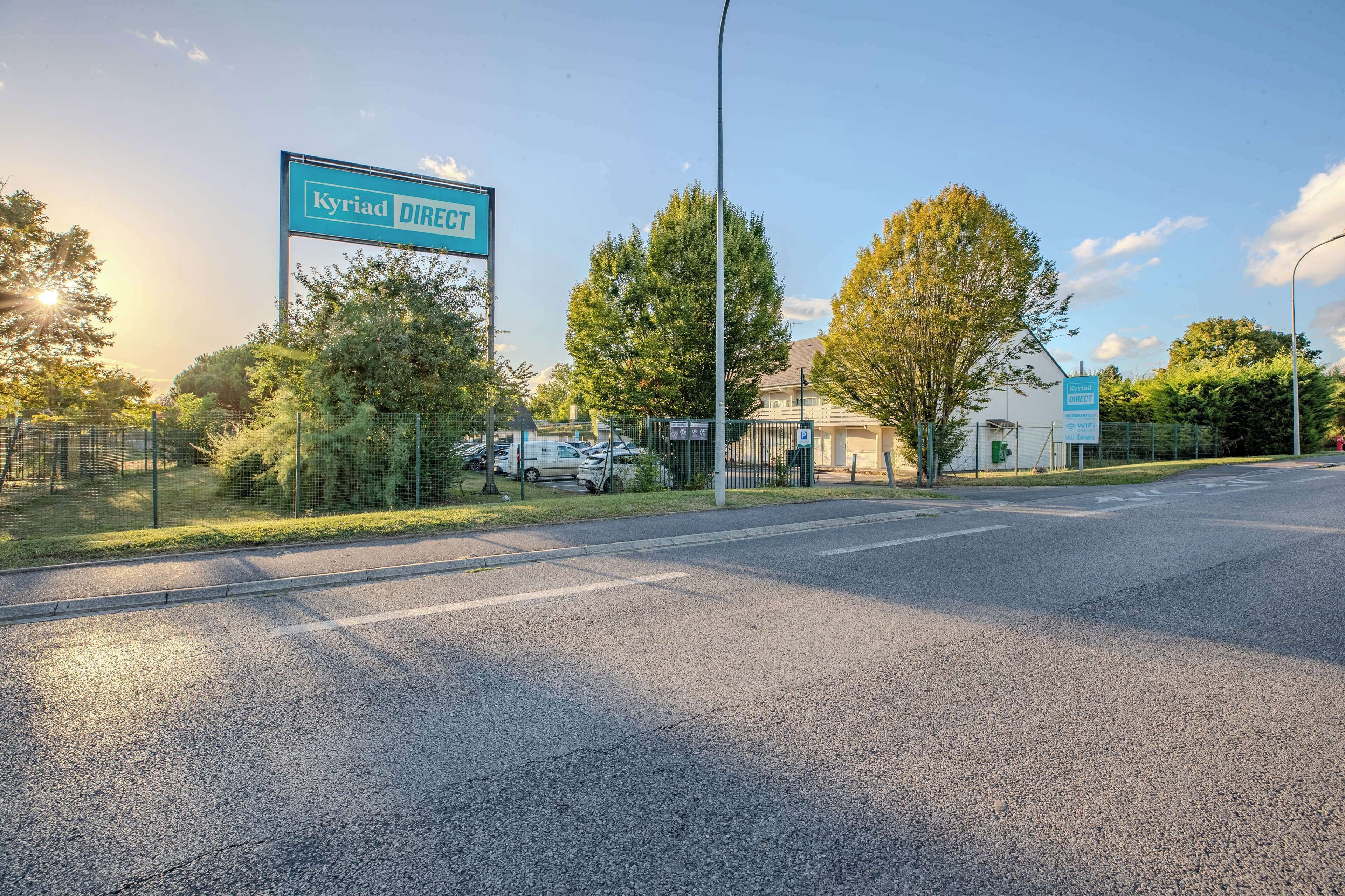 En vägskylt för ”Kyriad DIRECT” med en klar himmel och träd i bakgrunden.