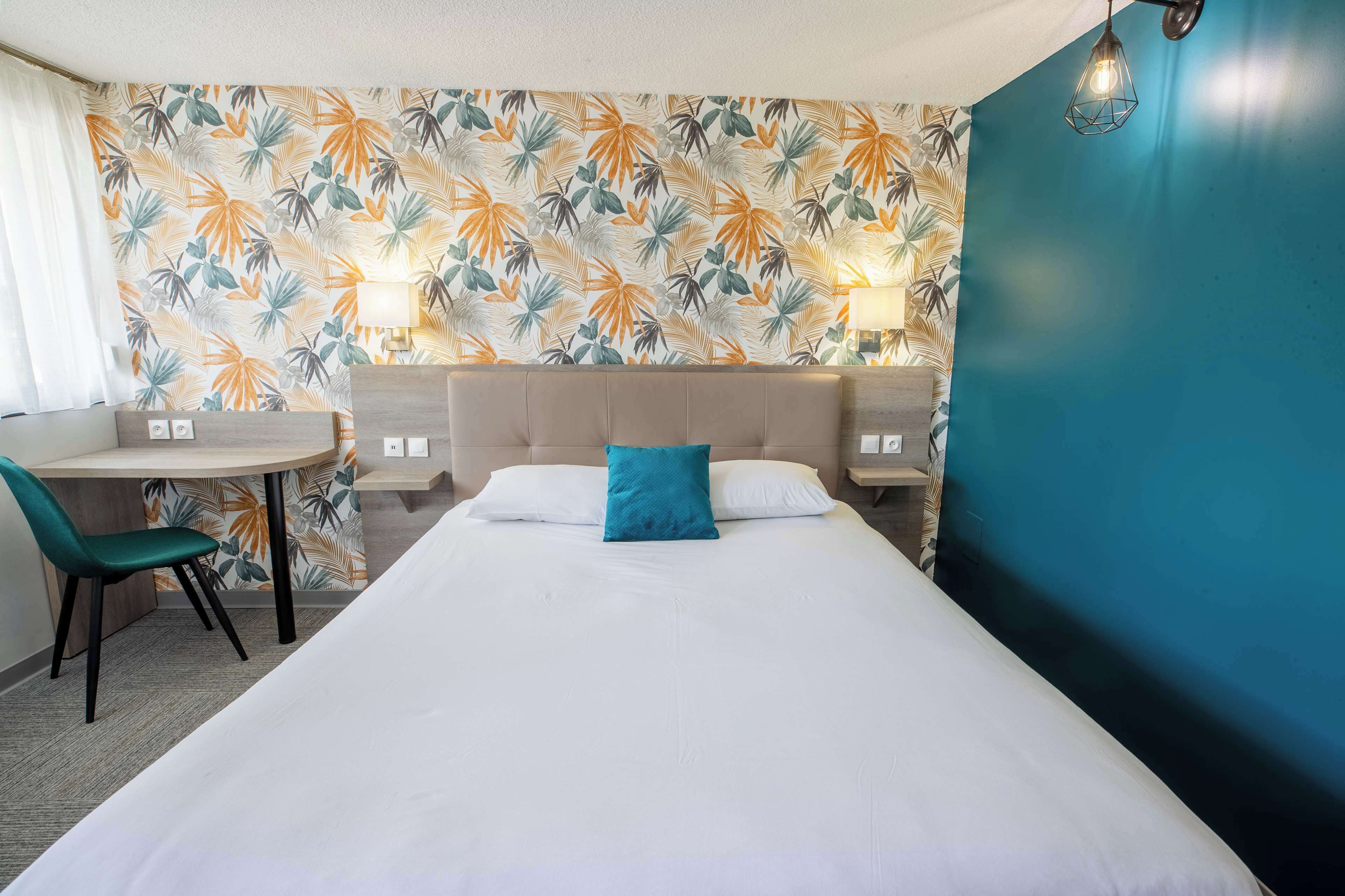 Hotellihuone, jossa on sänky, työpöytä ja kaksi tuolia.