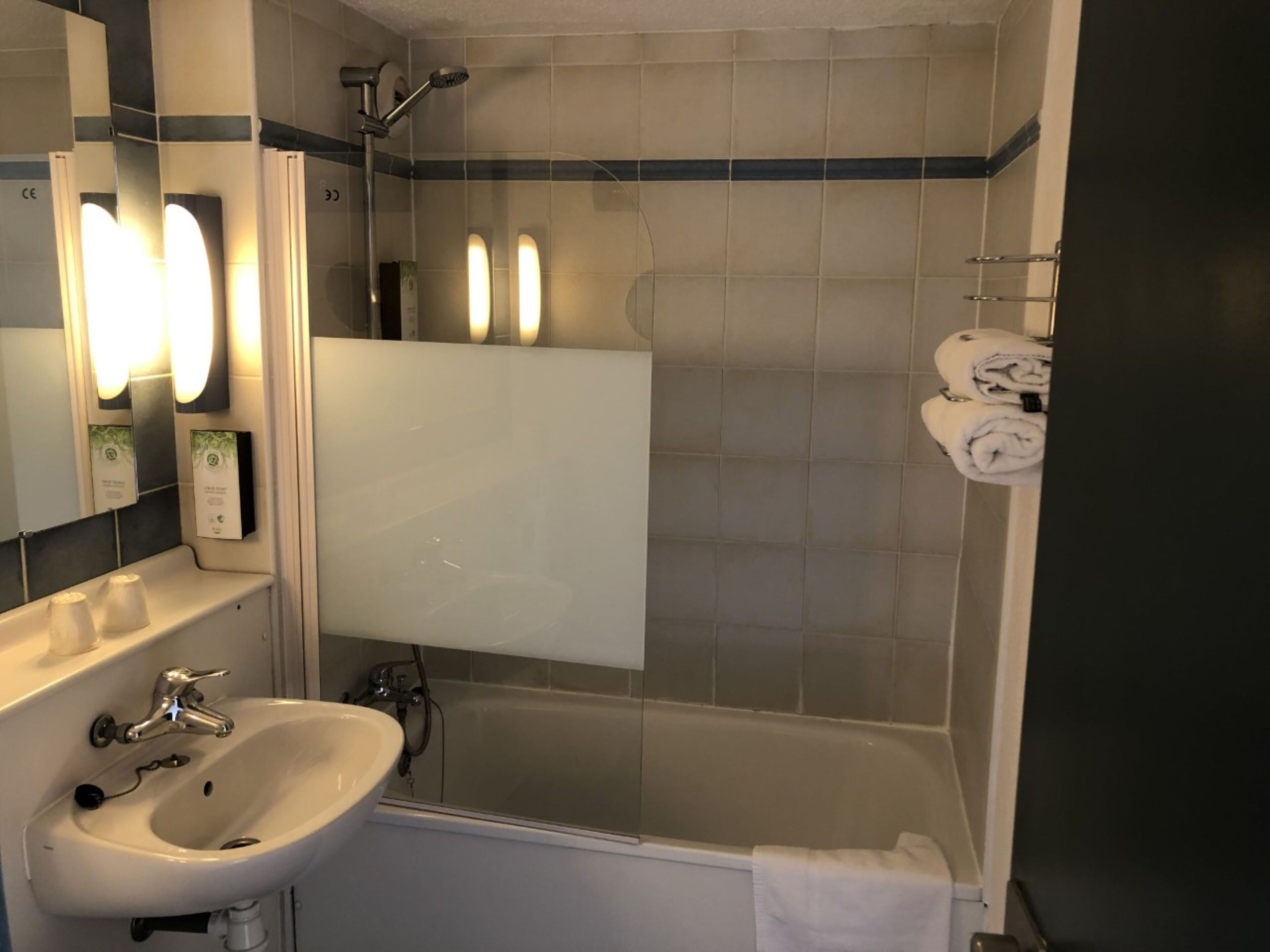 A bathroom with a sink, mirror, and shower.