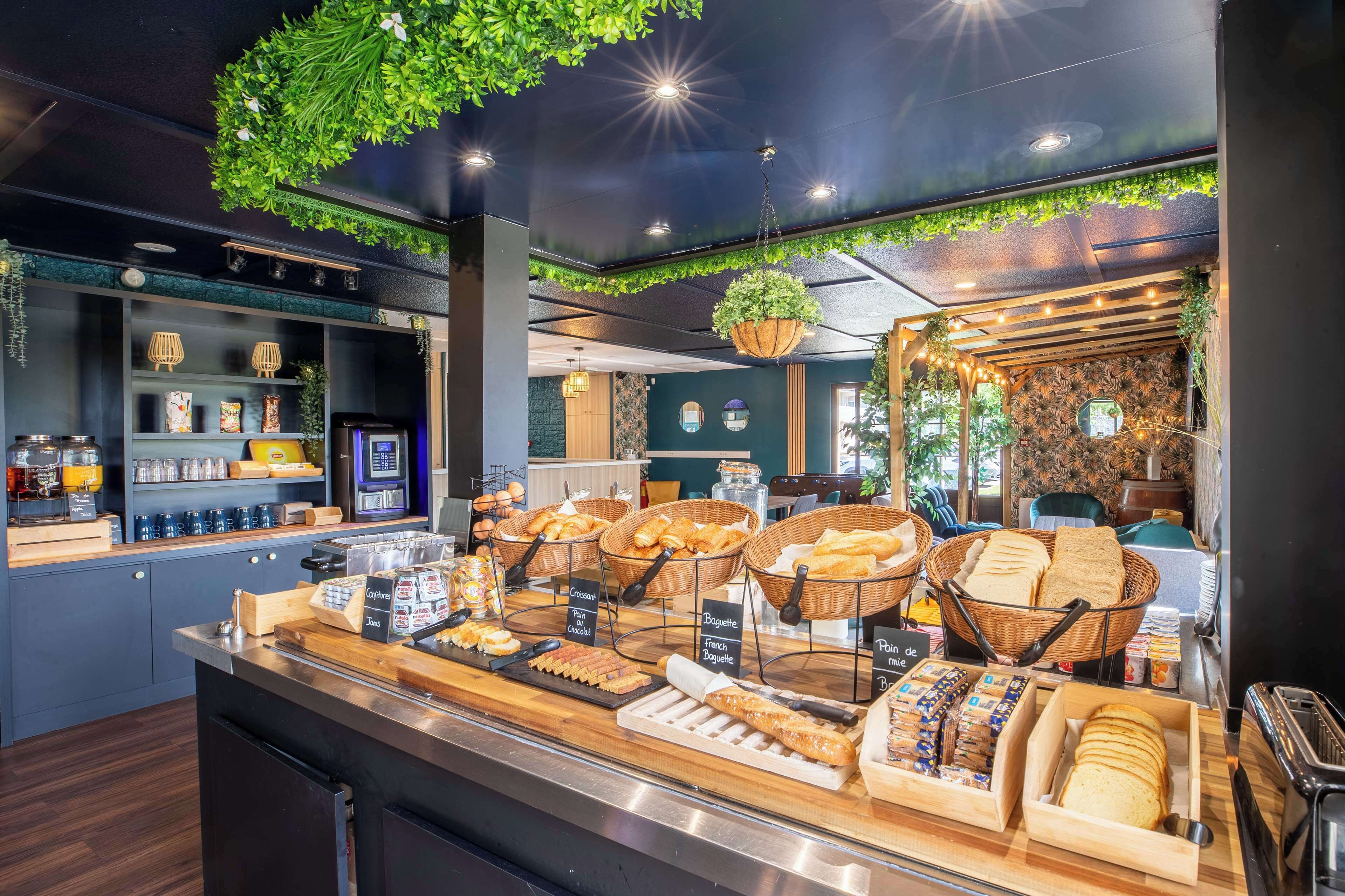 A breakfast buffet with various breads, pastries, and beverages.
